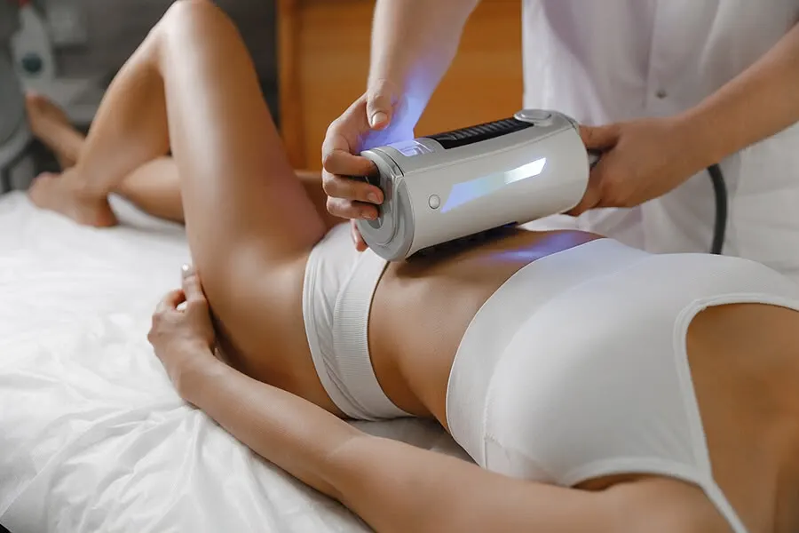 An abdominal session with the handpiece’s light visible against the skin